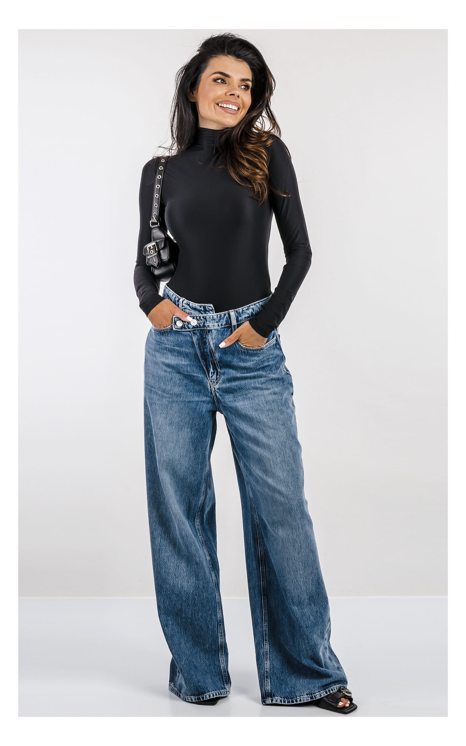 bluzka body guess w czarnym kolorze z golfem, dopasowany fason, z microfibry- stylizacja na modelce z jeansami wide leg i czarną torebką- widok z przodu