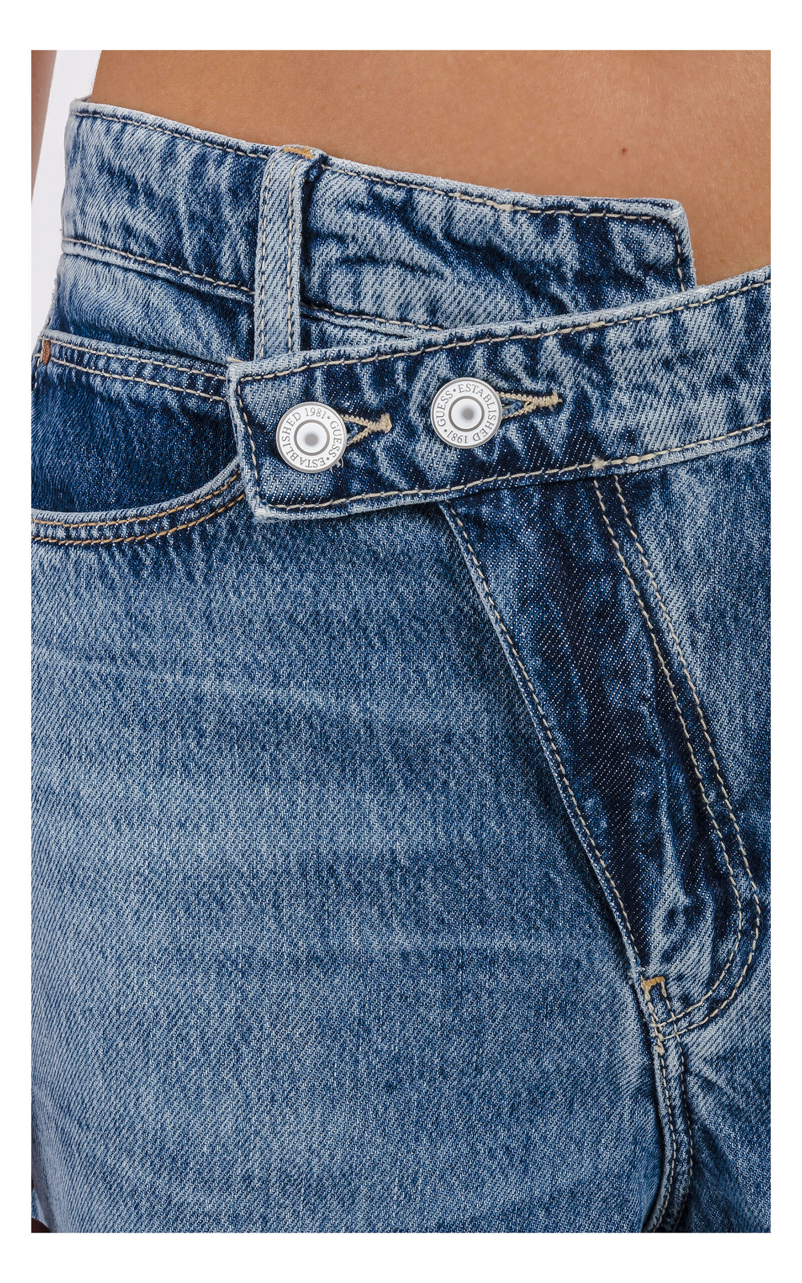 zbliżenie na asymetryczne zapięcie i logowane guziki jeansów guess