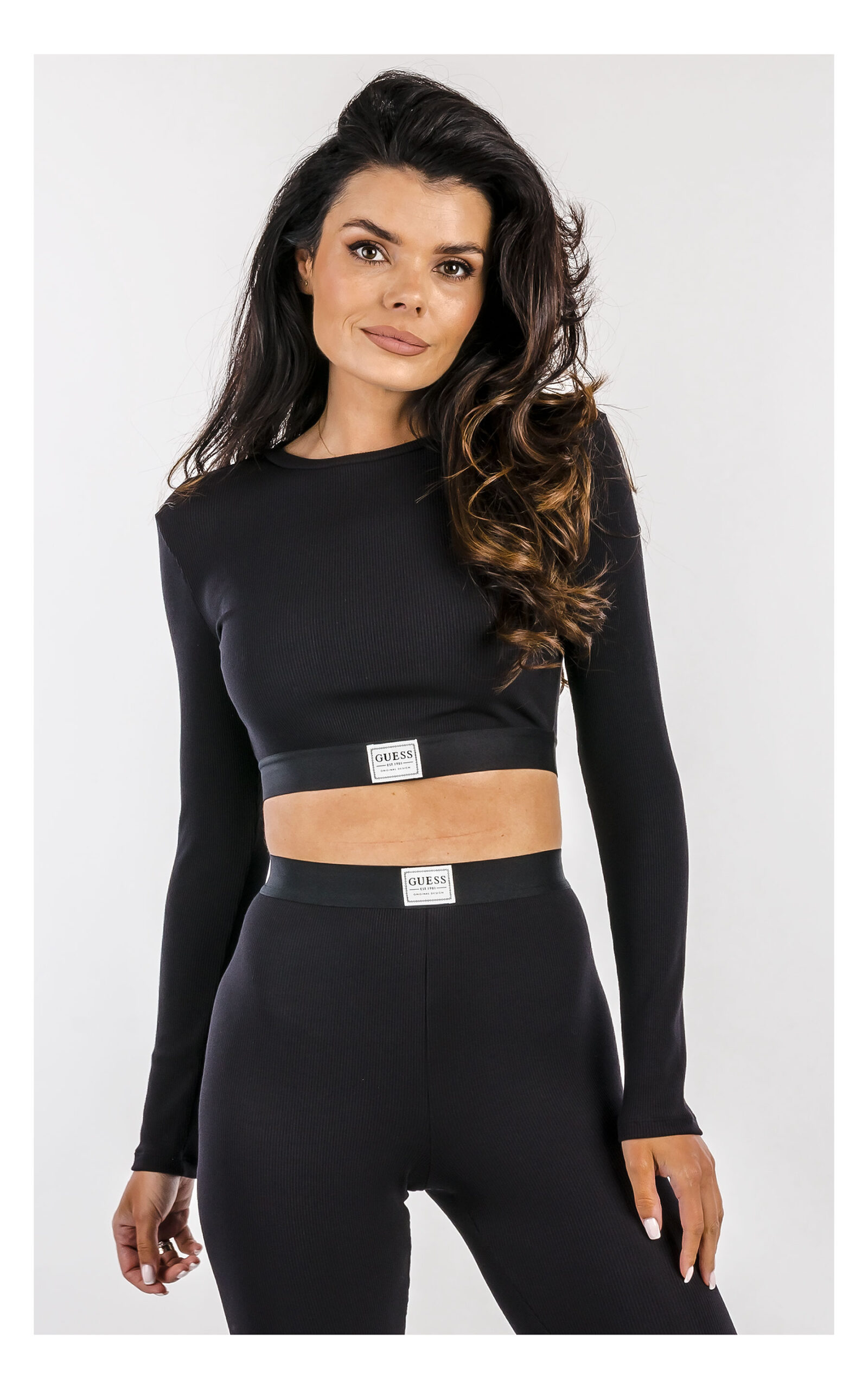 crop top w czarnym kolorze z tencelu marki guess z logowaną naszywką na modelce w zbliżeniu