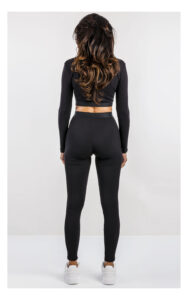 czarny crop top z długim rękawem, dopasowany z logowaną naszywką. Stylizacja z legginsami do kompletu. widok na modelce od tyłu