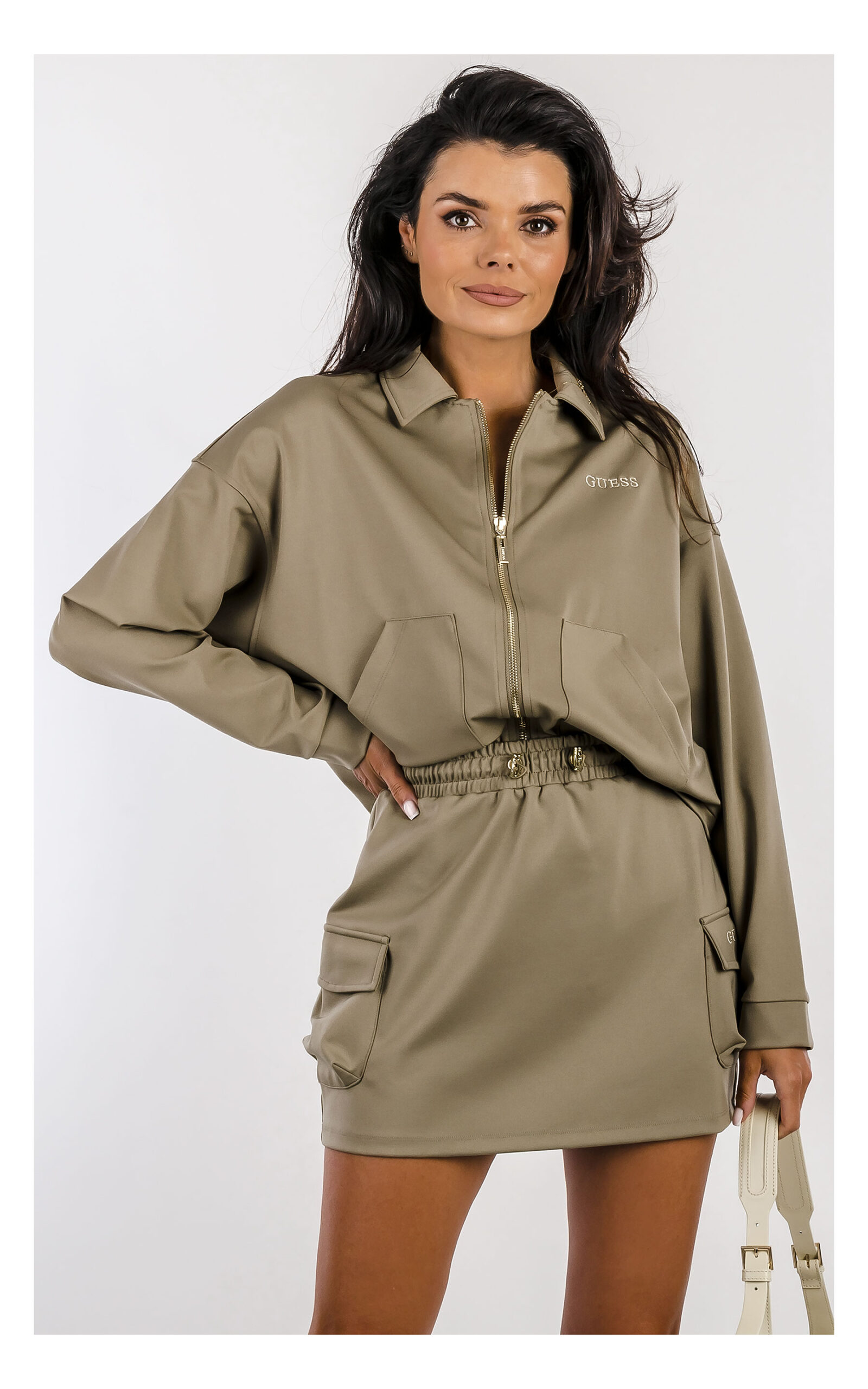 khaki bluza zapinana na zamek, fason luźny pudełkowy, z kołnierzykiem, logowany suwak oraz wyszywana nazwa marki, zestawiona z mini spódniczką cargo- widok na modelce w zbliżeniu