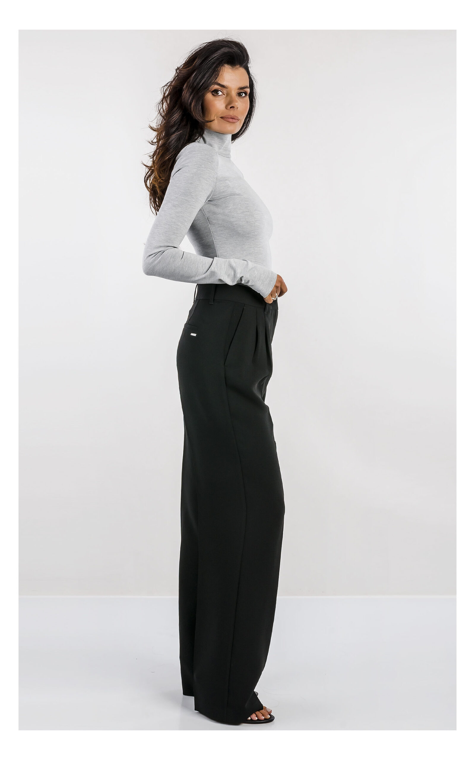 szara bluzka z golfem marki patrizia pepe zestawiona z czarnymi, eleganckimi spodniami z wysokim stanem- stylizacja na modelce z profilu