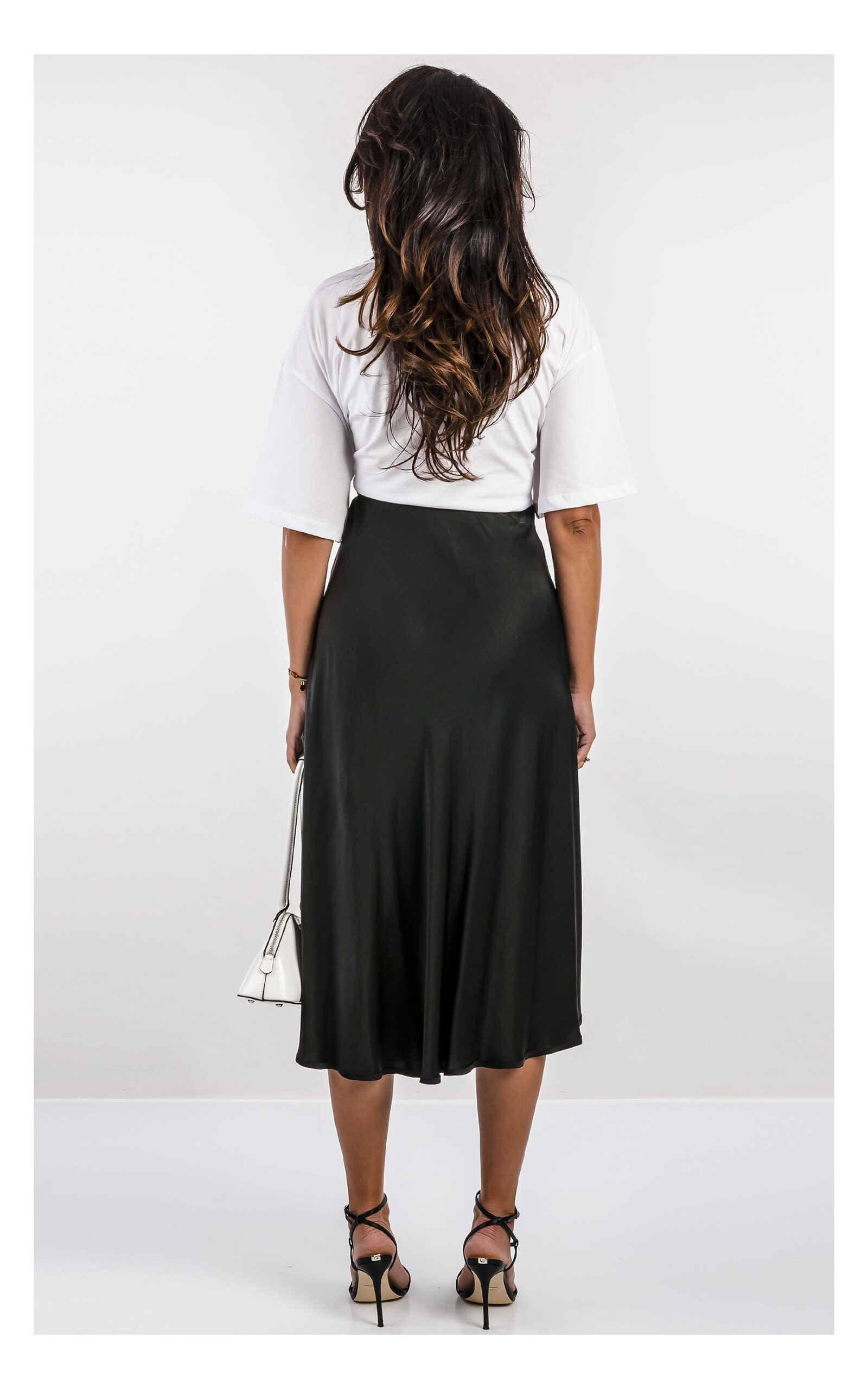 czarna satynowa spódnica midi fracomina o fasonie flare z wysokim stanem, elegancka, stylizacja z t-shirtem patrizia pepe- widok na modelce od tyłu