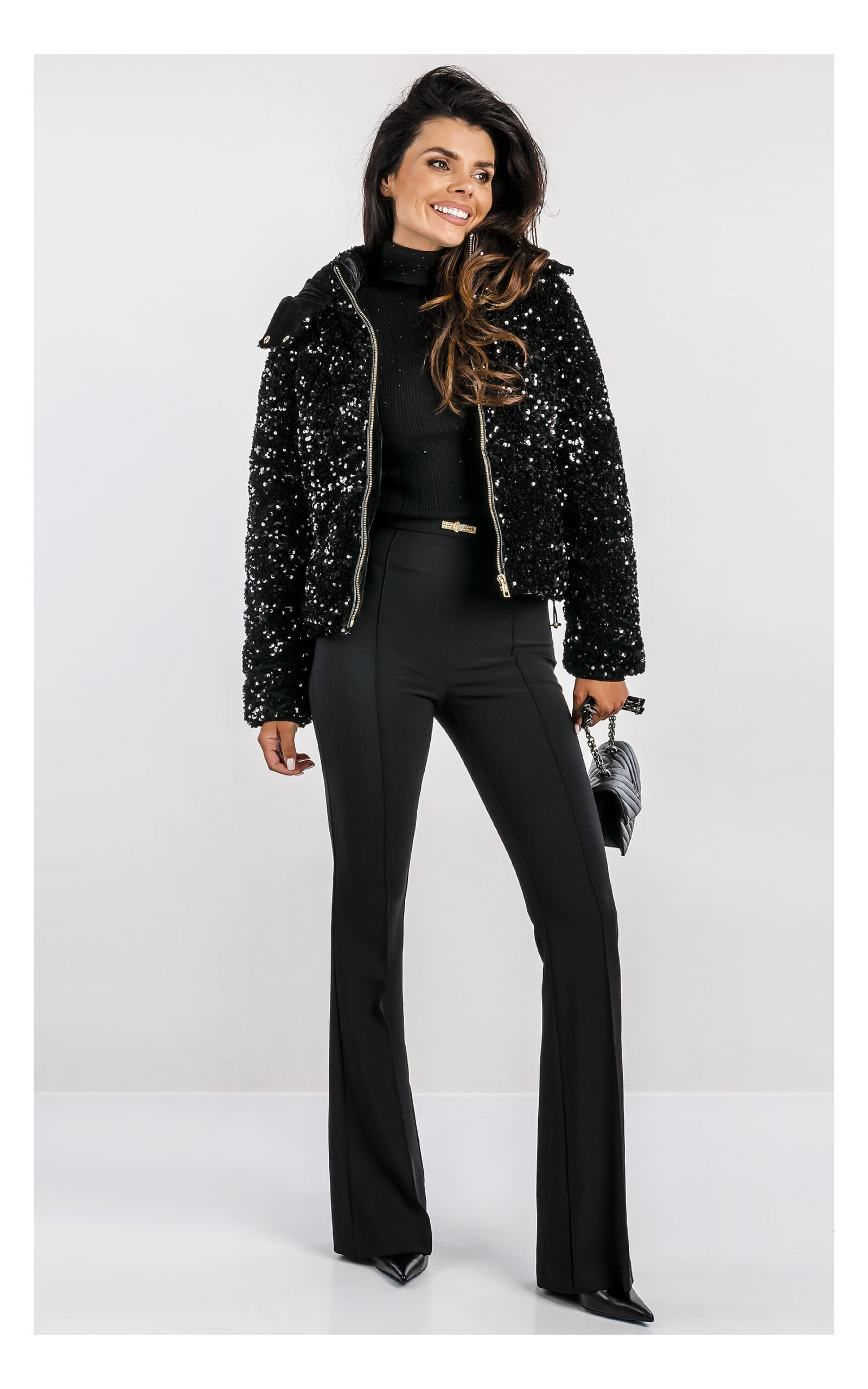 czarna kurtka cekinowa marki fracomina, fason regular fit, z kapturem - stylizacja z czarnymi eleganckimi spodniami typu flare- widok na modelce od przodu