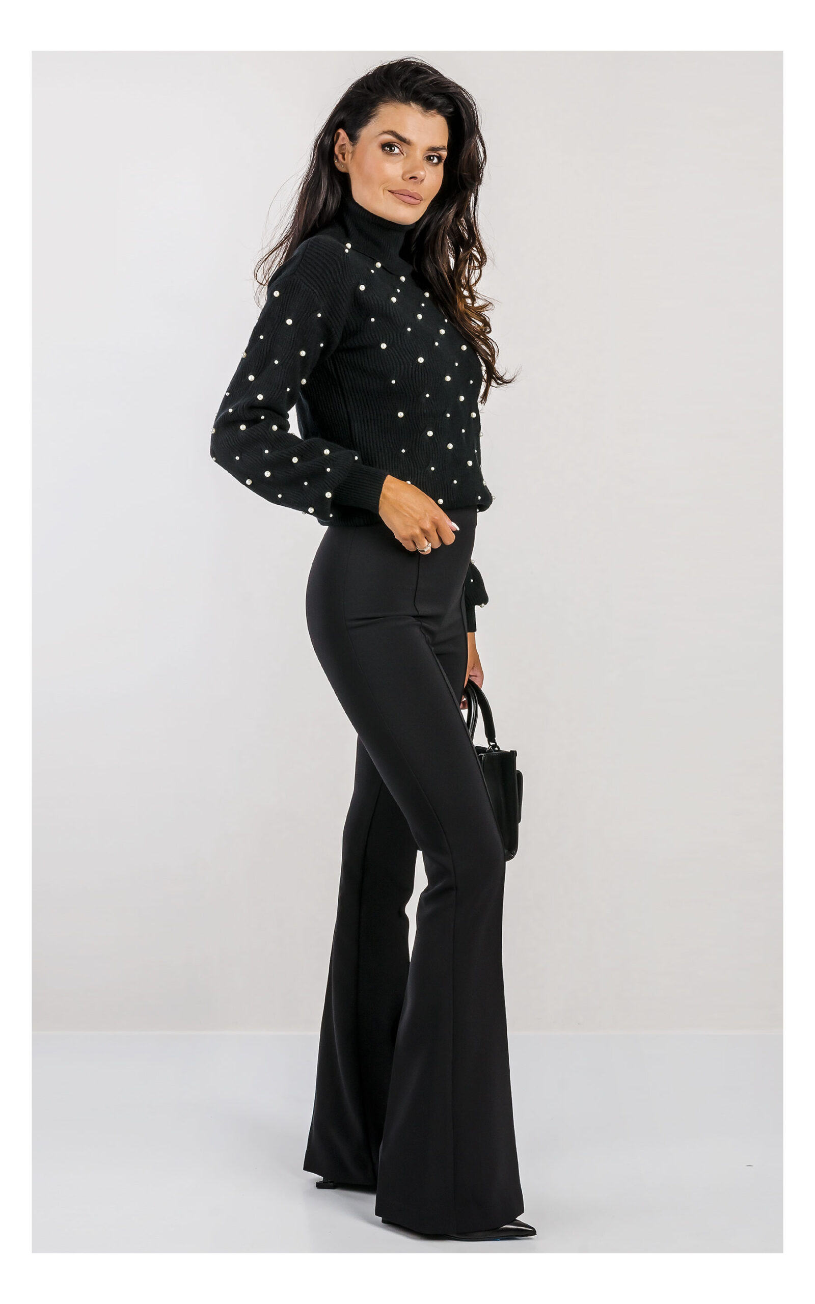 czarny sweter fracomina z miękkiej dzianiny z delikatnym splotem, zdobiony syntetycznymi perełkami, fason regular fit z golfem-stylizacja z czarnymi eleganckimi spodniami flare- widok na modelce z profilu