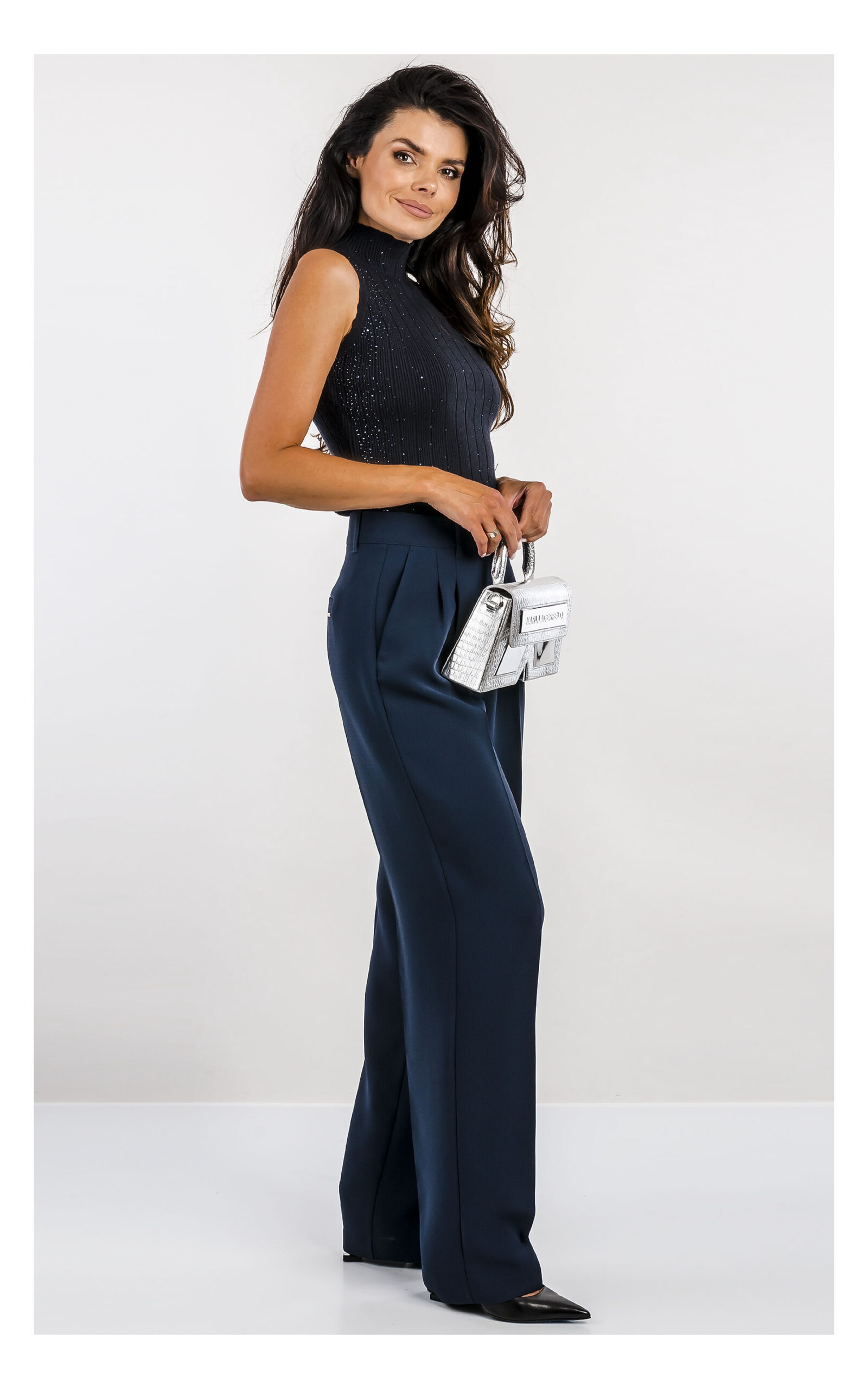 granatowy top fracomina z dzianiny zdobiony dżetami, fason slim fit z półgolfem- stylizacja z eleganckimi granatowymi spodniami- widok na modelce z profilu