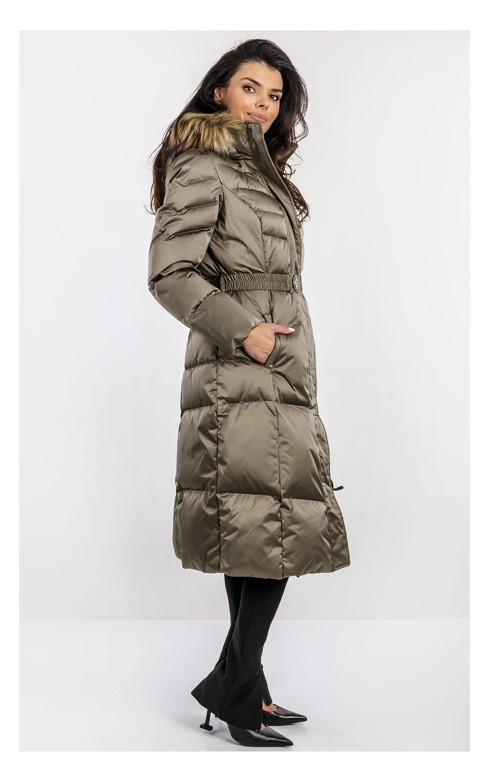 Khaki damski pikowany płaszcz Guess midi z paskiem w talii i zamkiem błyskawicznym, z kołnierzem i długimi rękawami, uszyty z wodoodpornego materiału, widok produktu na jasnym tle, na modelce z profilu