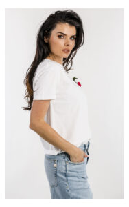 Biały basic T-shirt Twinset z szydełkową broszką – damska koszulka z krótkim rękawem i ozdobną broszką – modny top casual premium- widok na modelce z profilu w przybliżeniu