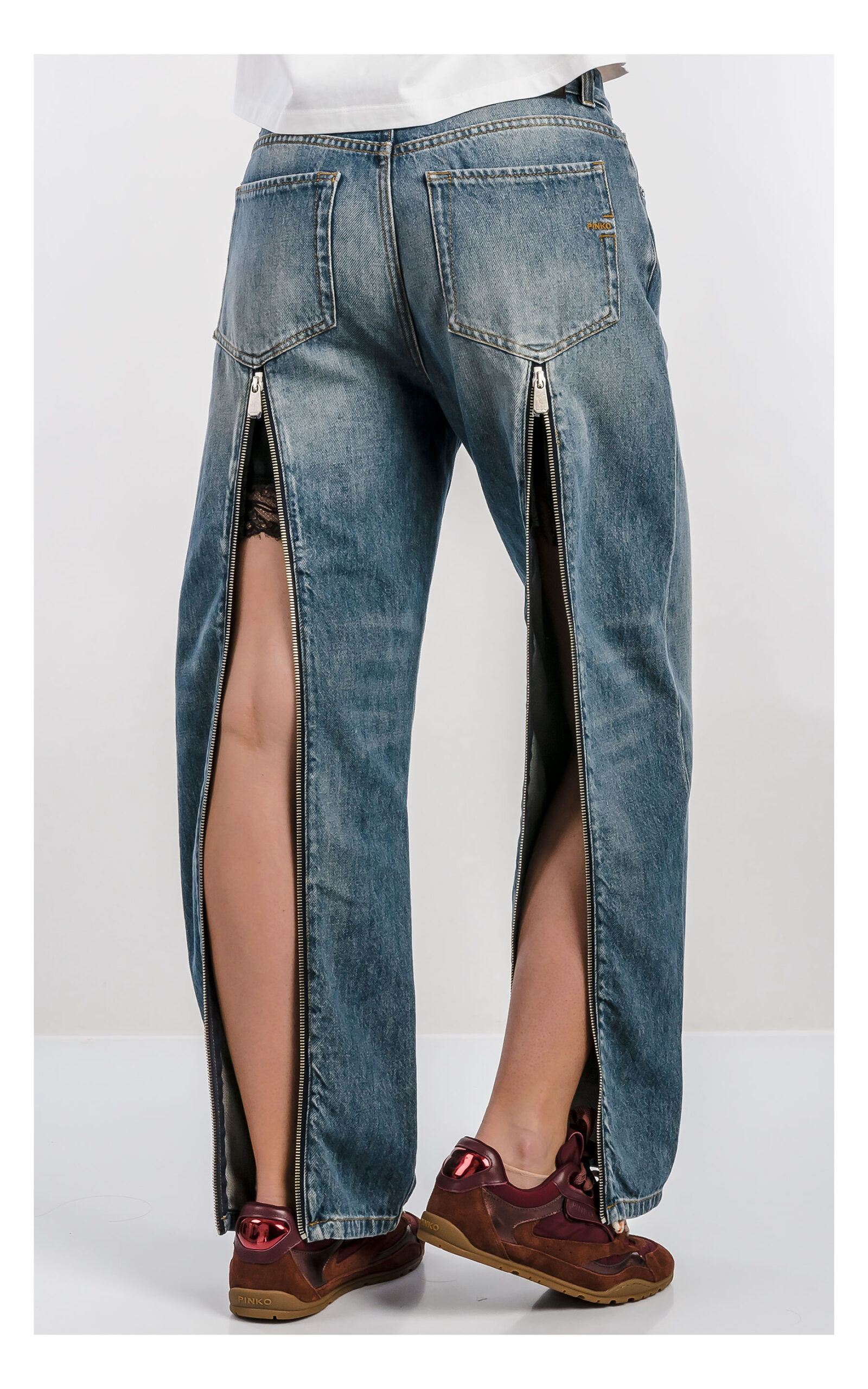 Damskie jeansy PINKO Lovely Loose w kolorze niebieskim z zamkami i koronką – luźne spodnie denim z detalami fashion – idealne do casualowych stylizacji- widok na modelce od pasa w dół od tyłu z rozsuniętymi zamkami