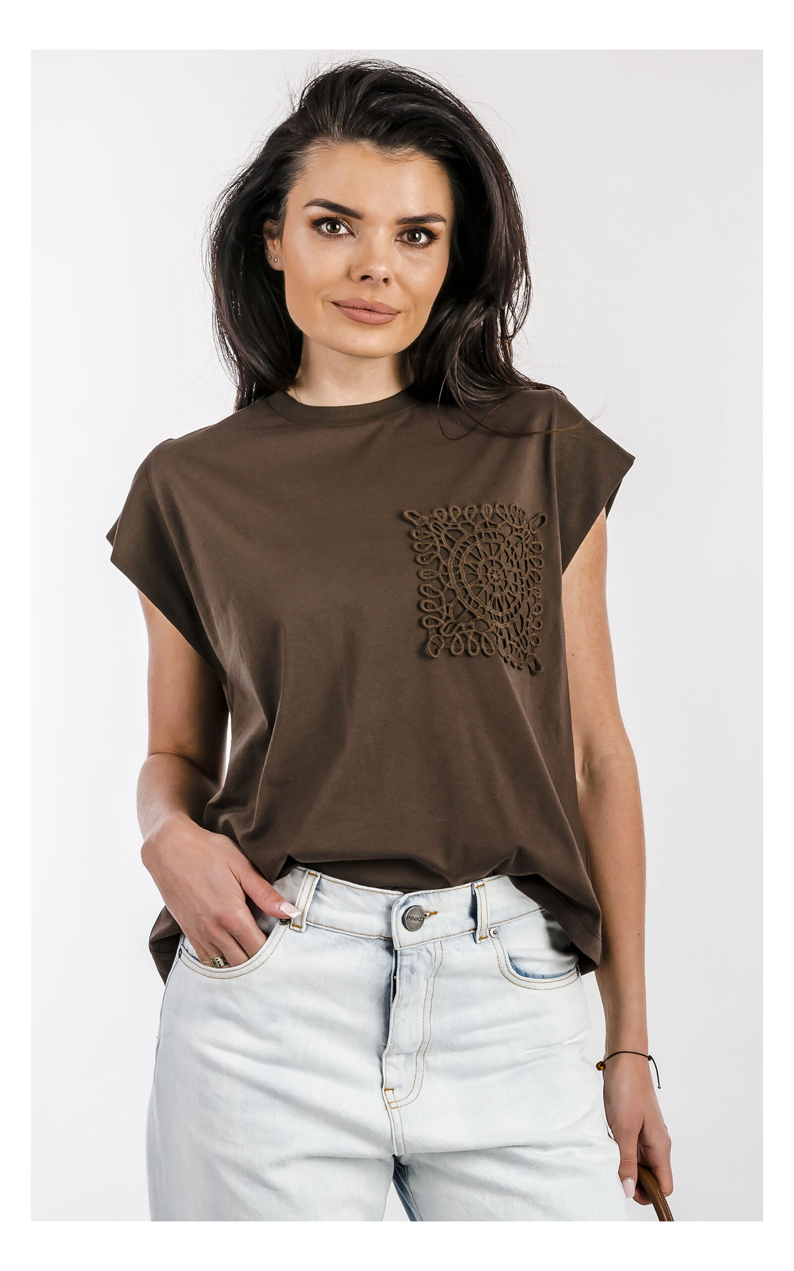 Brązowy T-shirt ACCESS z haftowaną aplikacją i krótkim rękawem – damska koszulka bawełniana casual – modny top z detalem haftu, idealny do codziennych stylizacji- widok na modelce od przodu w przybliżeniu