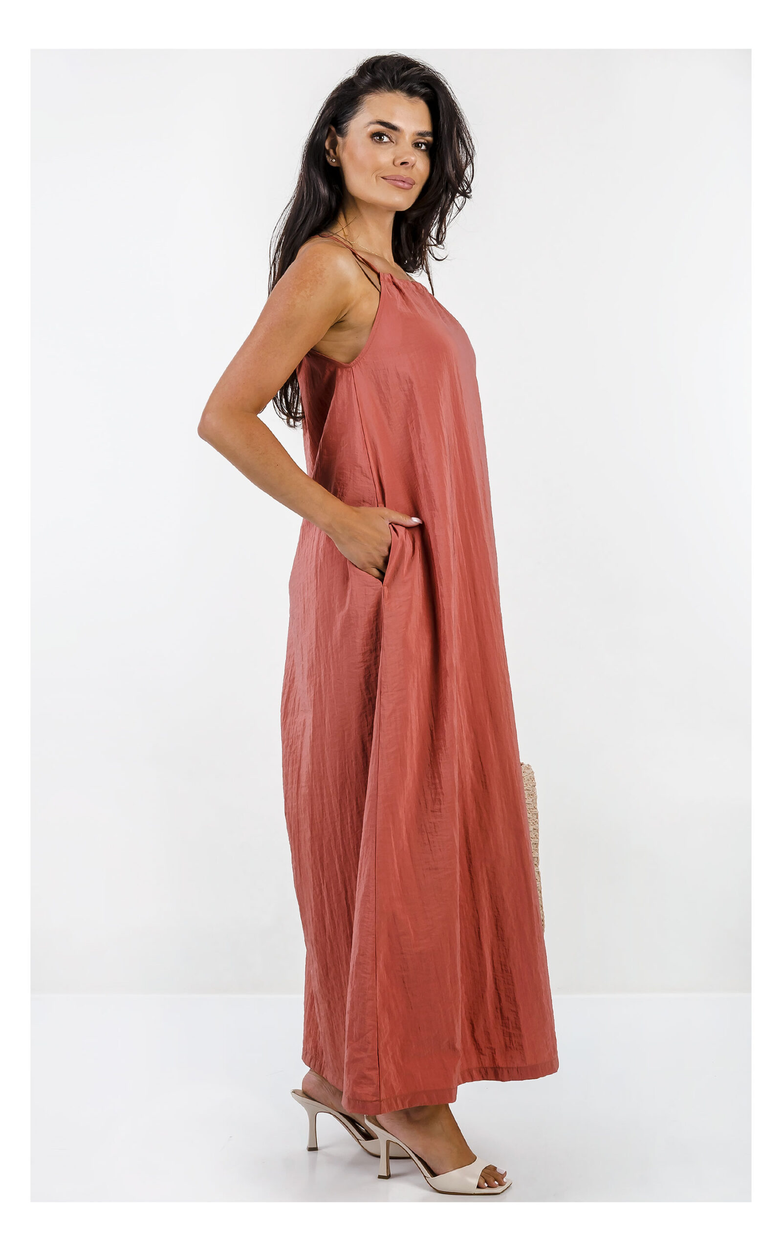 Pomarańczowa sukienka maxi Emporio Armani o prostym fasonie wykonana z lekkiego, komfortowego materiału. Widok na modelkę w całości z profilu.