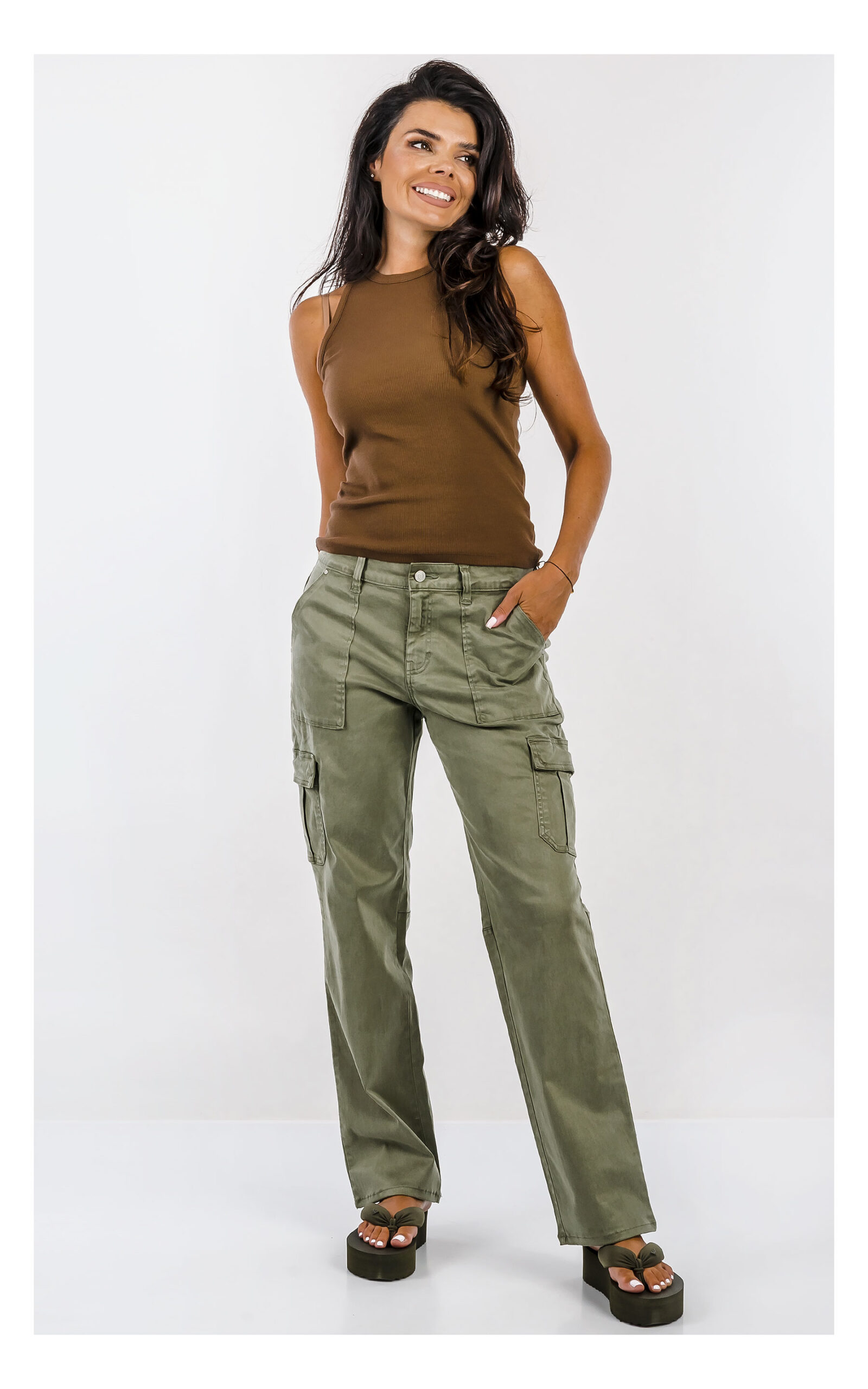 Spodnie GUESS cargo oliwkowe z wysokim stanem i praktycznymi kieszeniami, casualowy model damski o modnym fasonie. Widok na modelce w całości od przodu.
