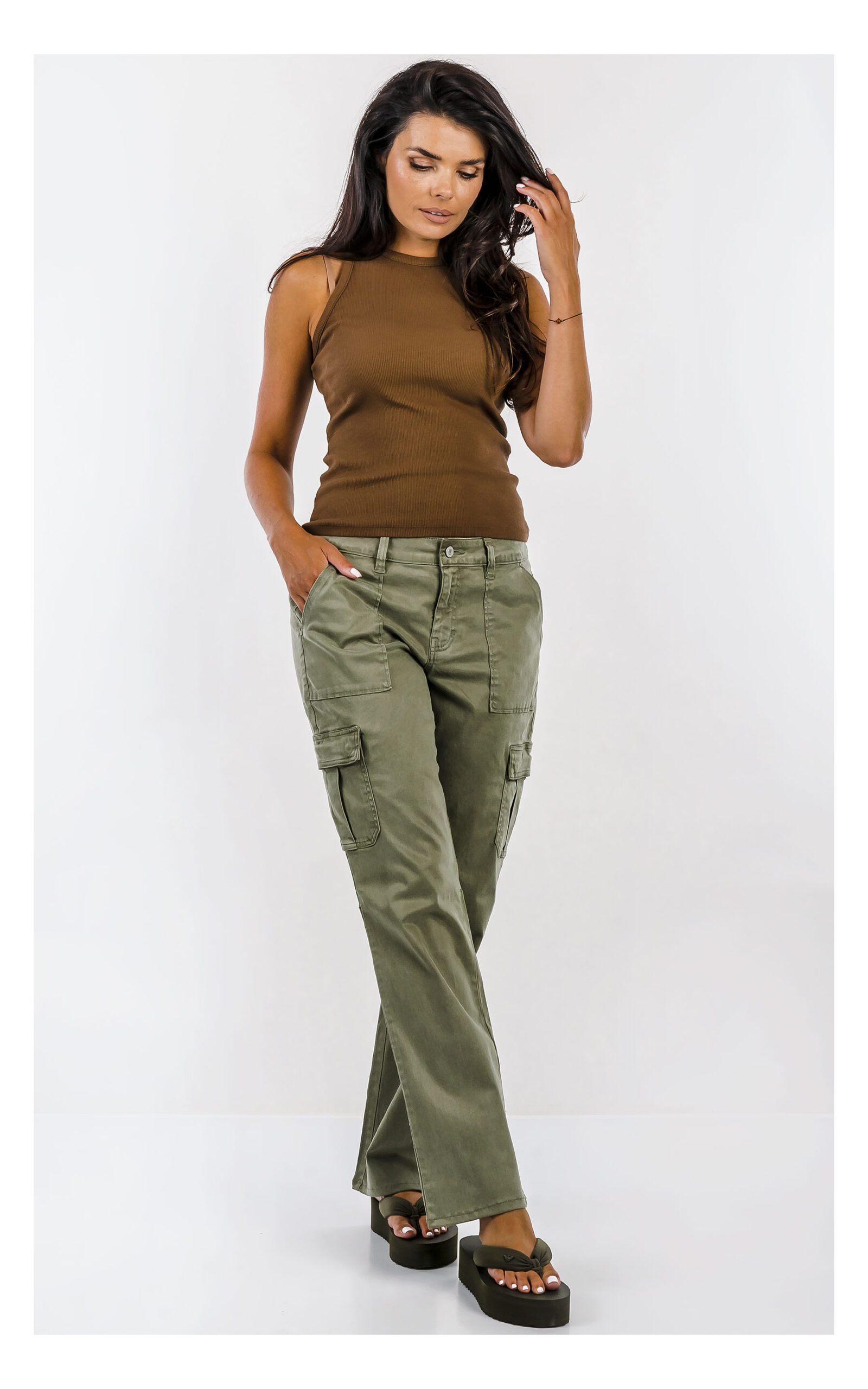 Spodnie GUESS cargo oliwkowe z wysokim stanem i praktycznymi kieszeniami, casualowy model damski o modnym fasonie. Widok na modelce w całości od przodu.